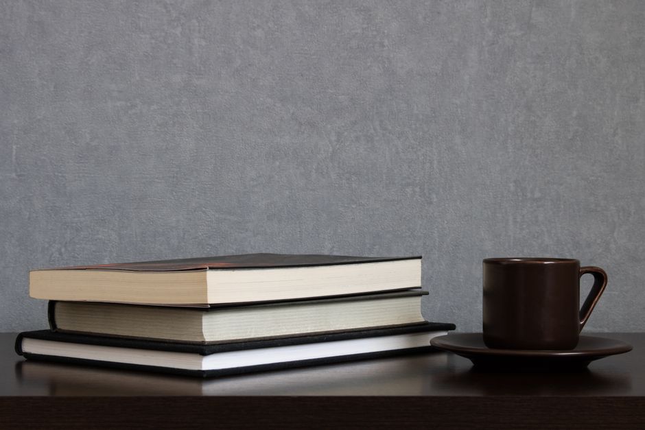 A serene scene featuring books, a coffee cup, and shadows creating a cozy ambiance.
