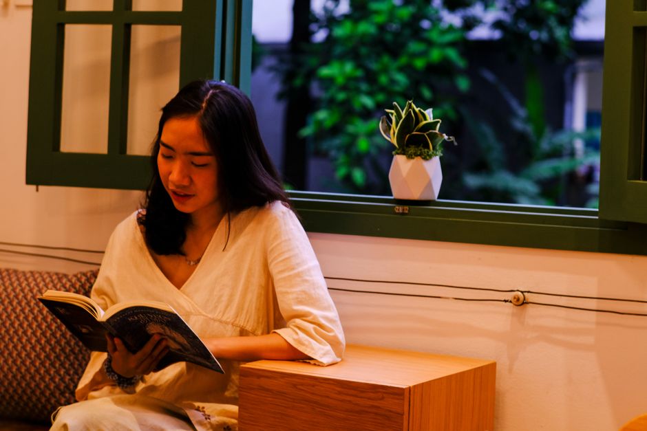 A serene moment of a woman reading by the window in Hue, Vietnam.