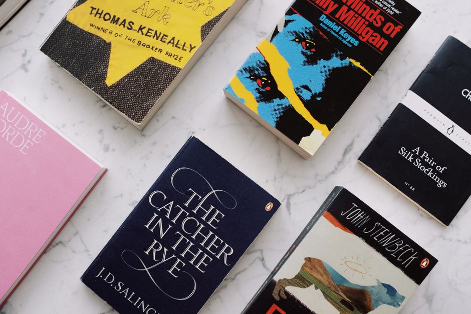 Top view of collection with famous novels with colorful inscriptions and covers arranged on white marble surface