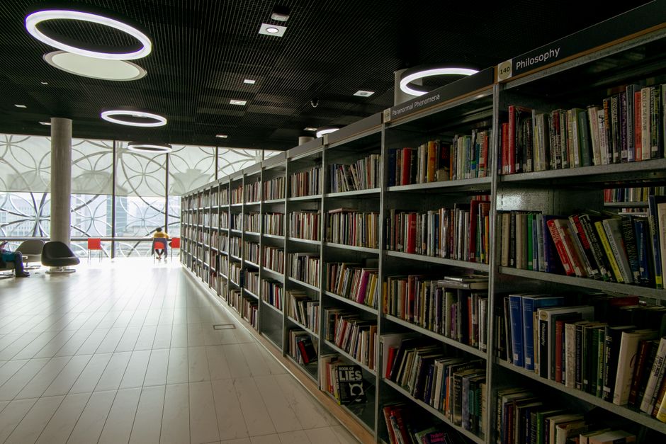 A quiet modern library interior with bookshelves and bright circular lights.